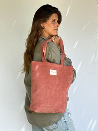 Model carrying the DE LA MUR coral corduroy tote bag over her shoulder