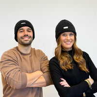 Two models wearing the DE LA MUR Sherpa Beanie in black, lifestyle shot