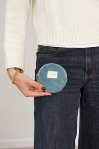 Model holding DE LA MUR teal corduroy round coin purse at jeans pocket, lifestyle shot