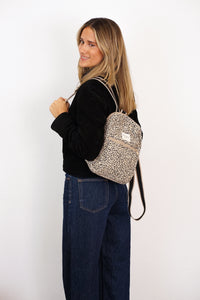 Model wearing the DE LA MUR Leopard Jacquard Small Backpack in beige and black, side view