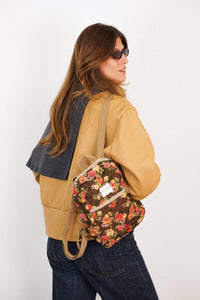 Model wearing the DE LA MUR Pepi floral jacquard small backpack, lifestyle view