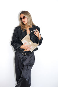 Model in a sequin jacket holding the DE LA MUR champagne gold velvet Small Evening Bag