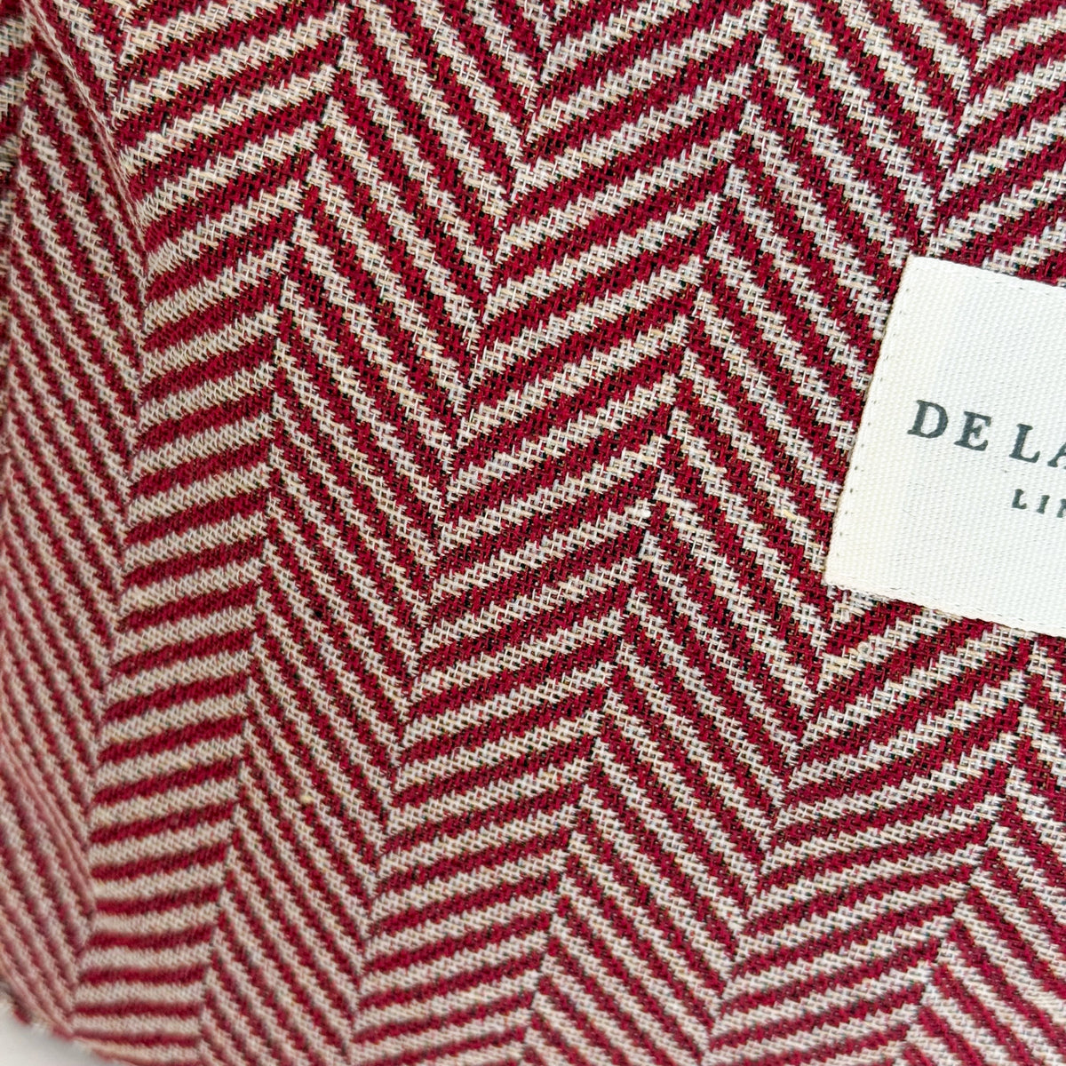 Close-up of the red and beige herringbone jacquard weave and DE LA MUR Line label