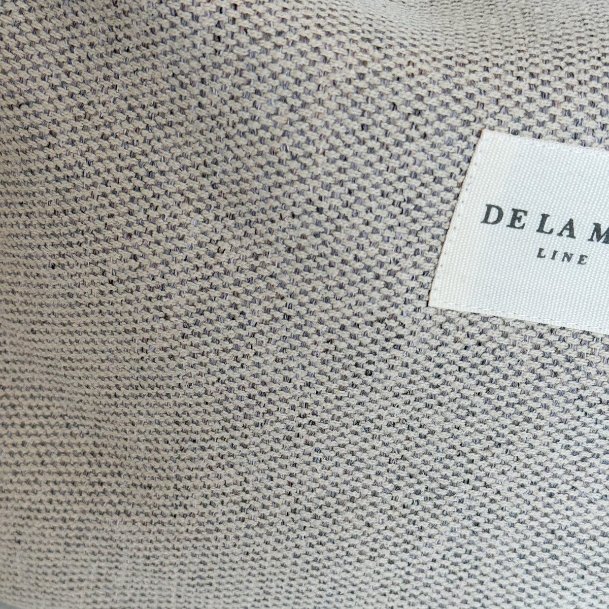 Close-up of the woven herringbone fabric and DE LA MUR Line label on the Sydney bag