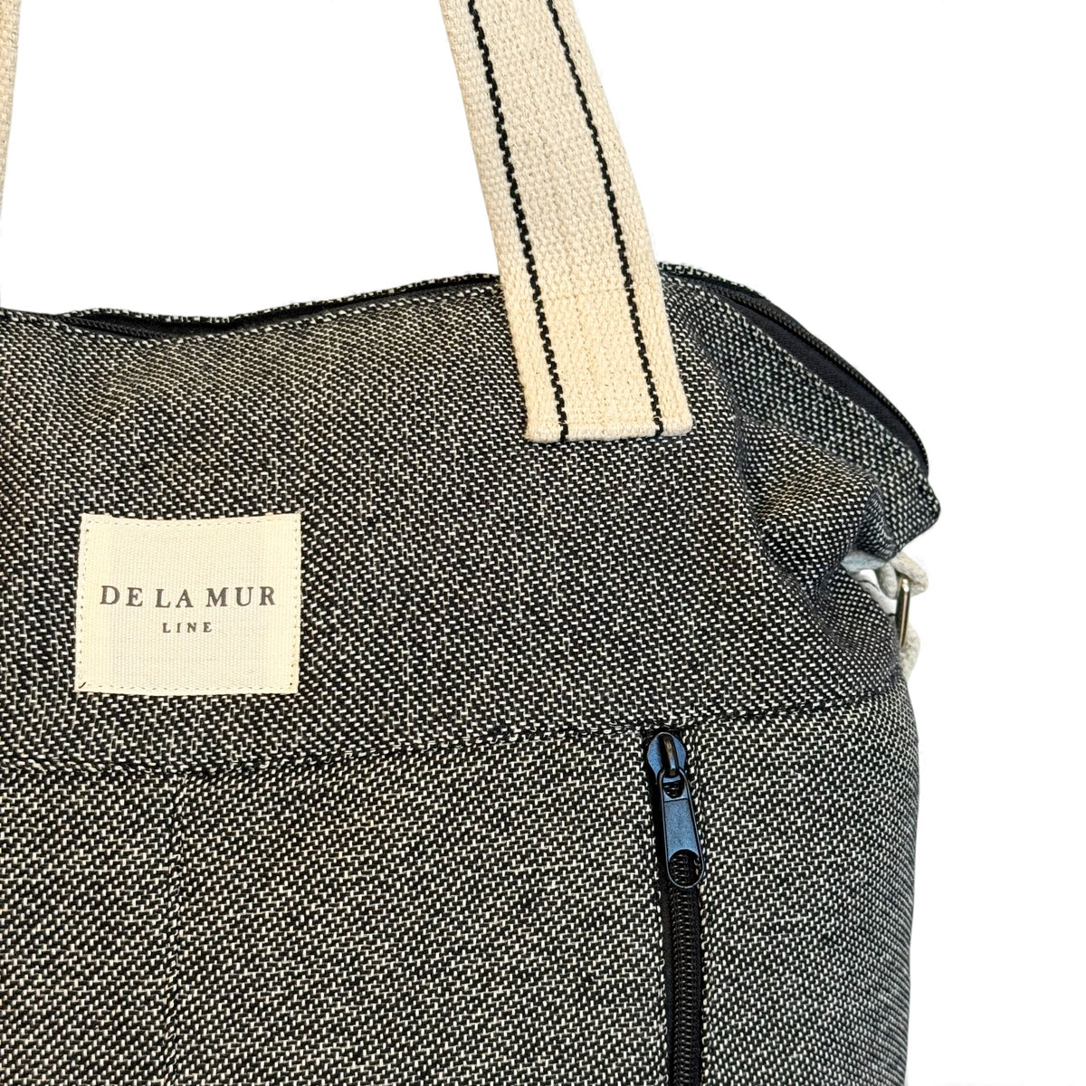 Close-up of the DE LA MUR Line label and exterior zip pocket on the Sinay bag