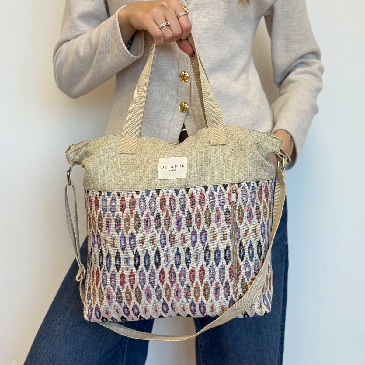 Model holding the DE LA MUR Urban geometric jacquard handbag, three-quarter view