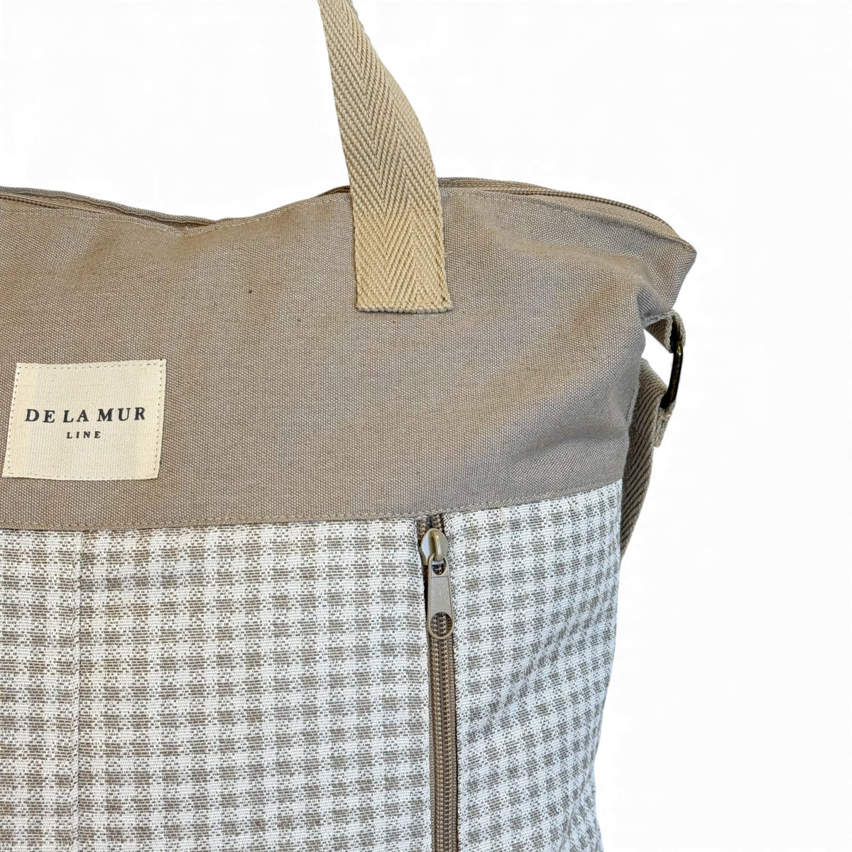 Close-up of the DE LA MUR Line label and exterior zip on the Vison handbag