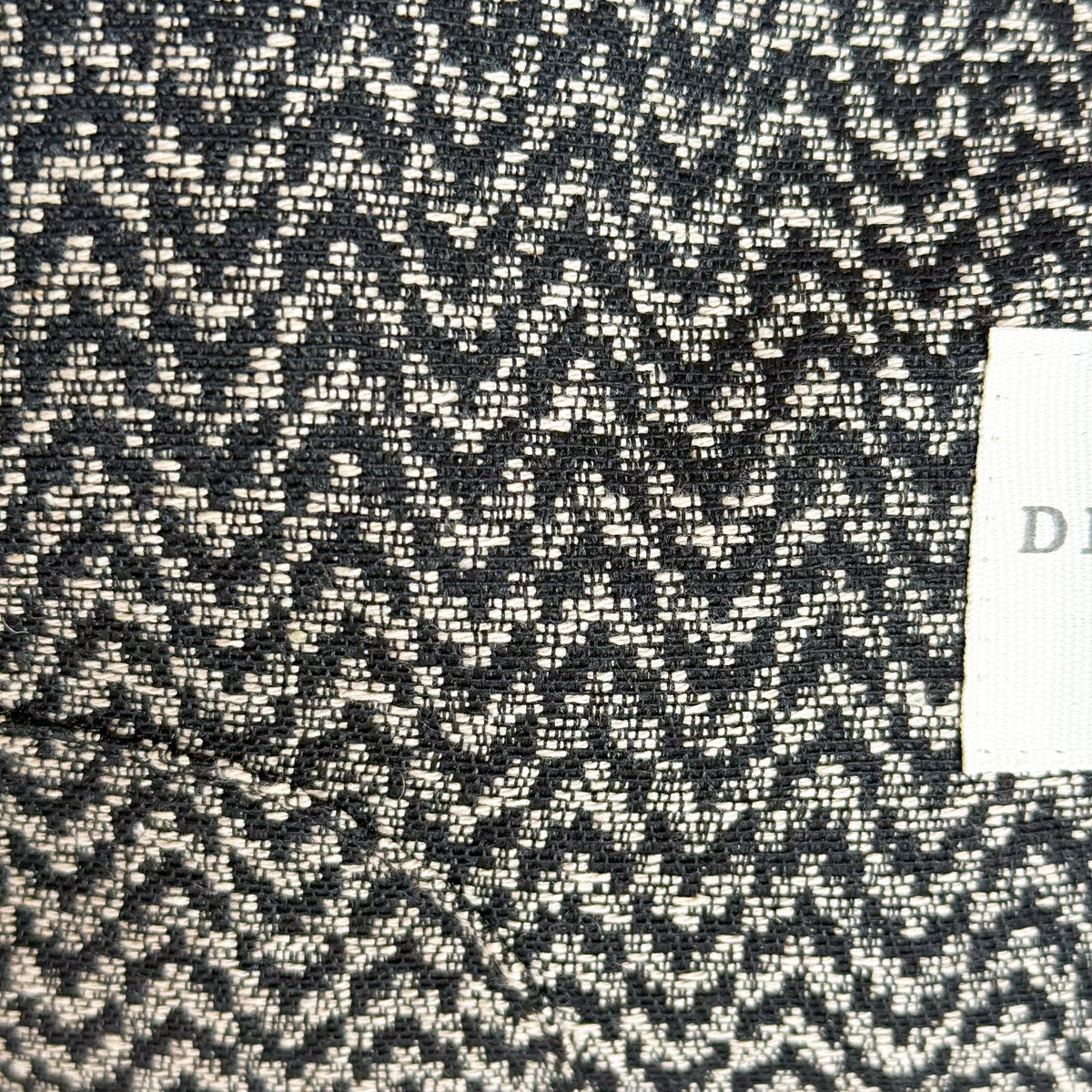 Close-up of the black and beige zigzag jacquard weave with DE LA MUR label
