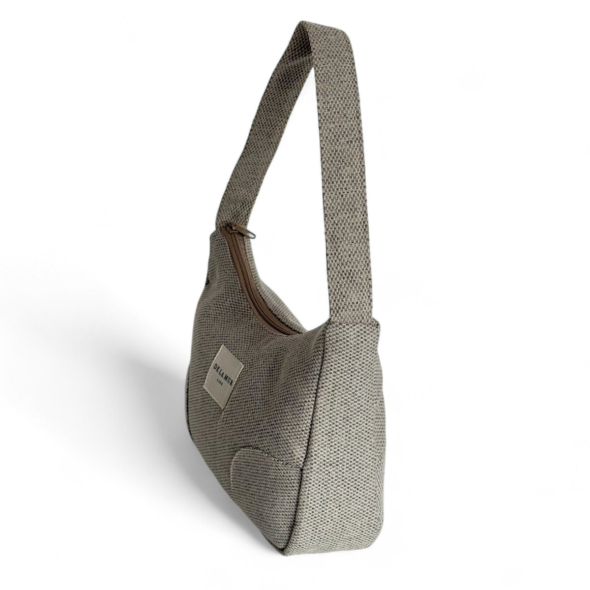 Three-quarter view of the DE LA MUR Sydney beige shoulder bag with strap