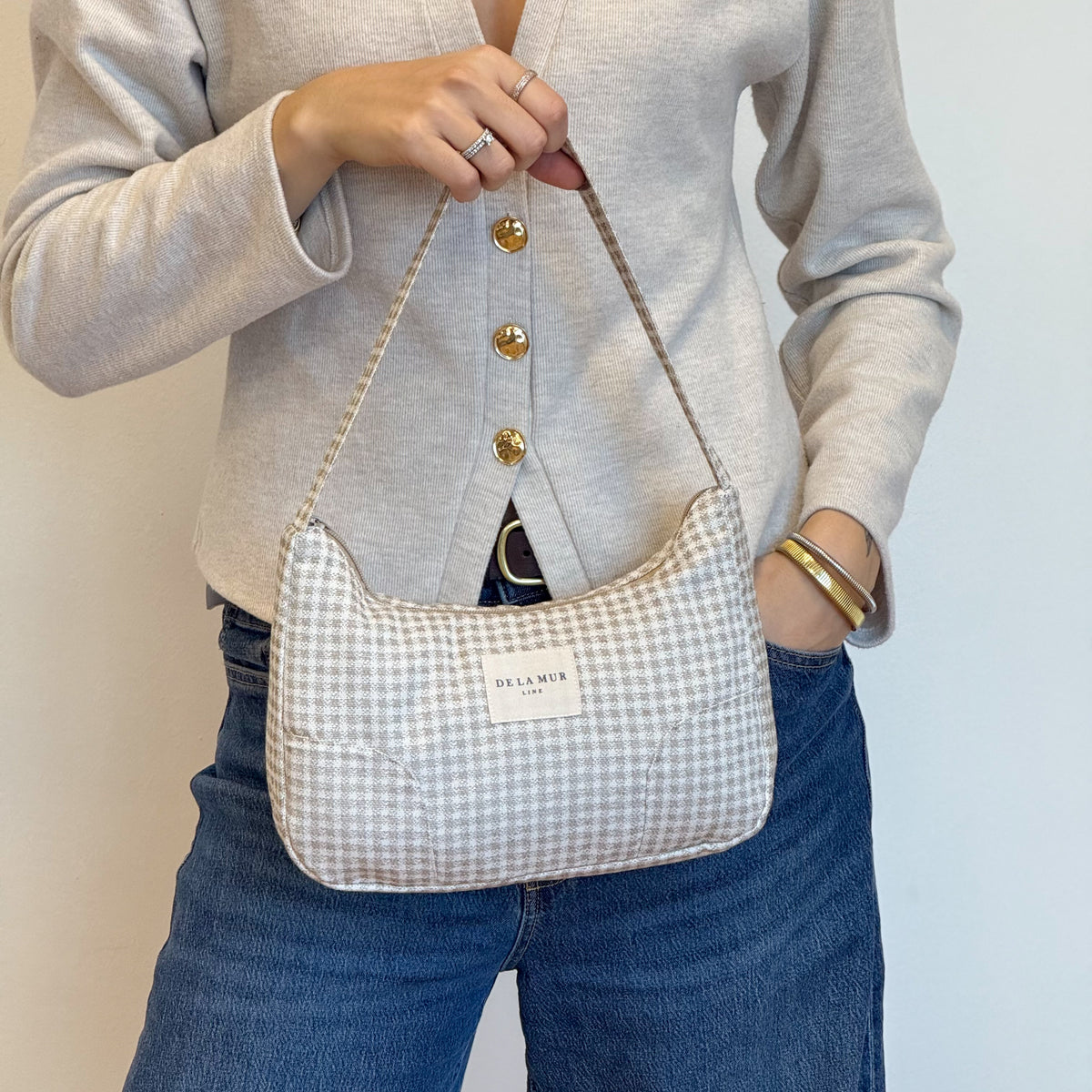 Model holding the DE LA MUR Vison gingham shoulder bag, lifestyle shot