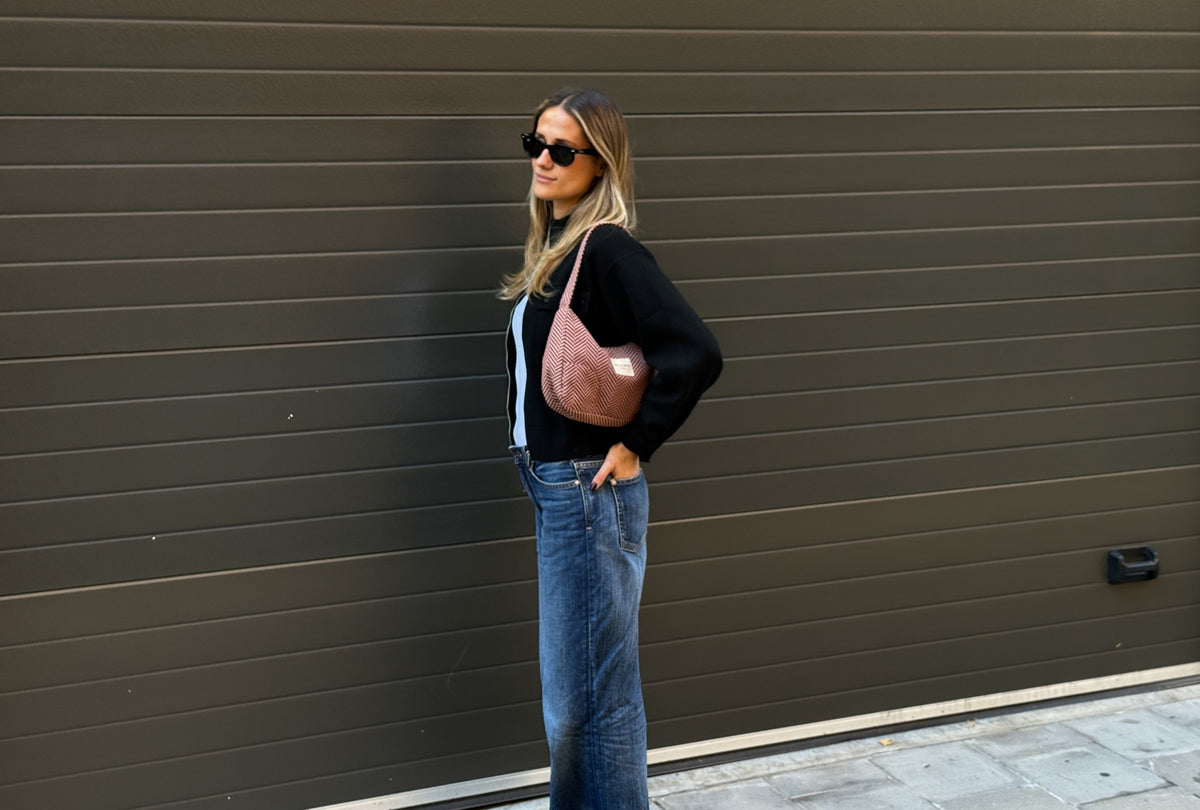 Model carrying the DE LA MUR Dubai herringbone shoulder bag outdoors