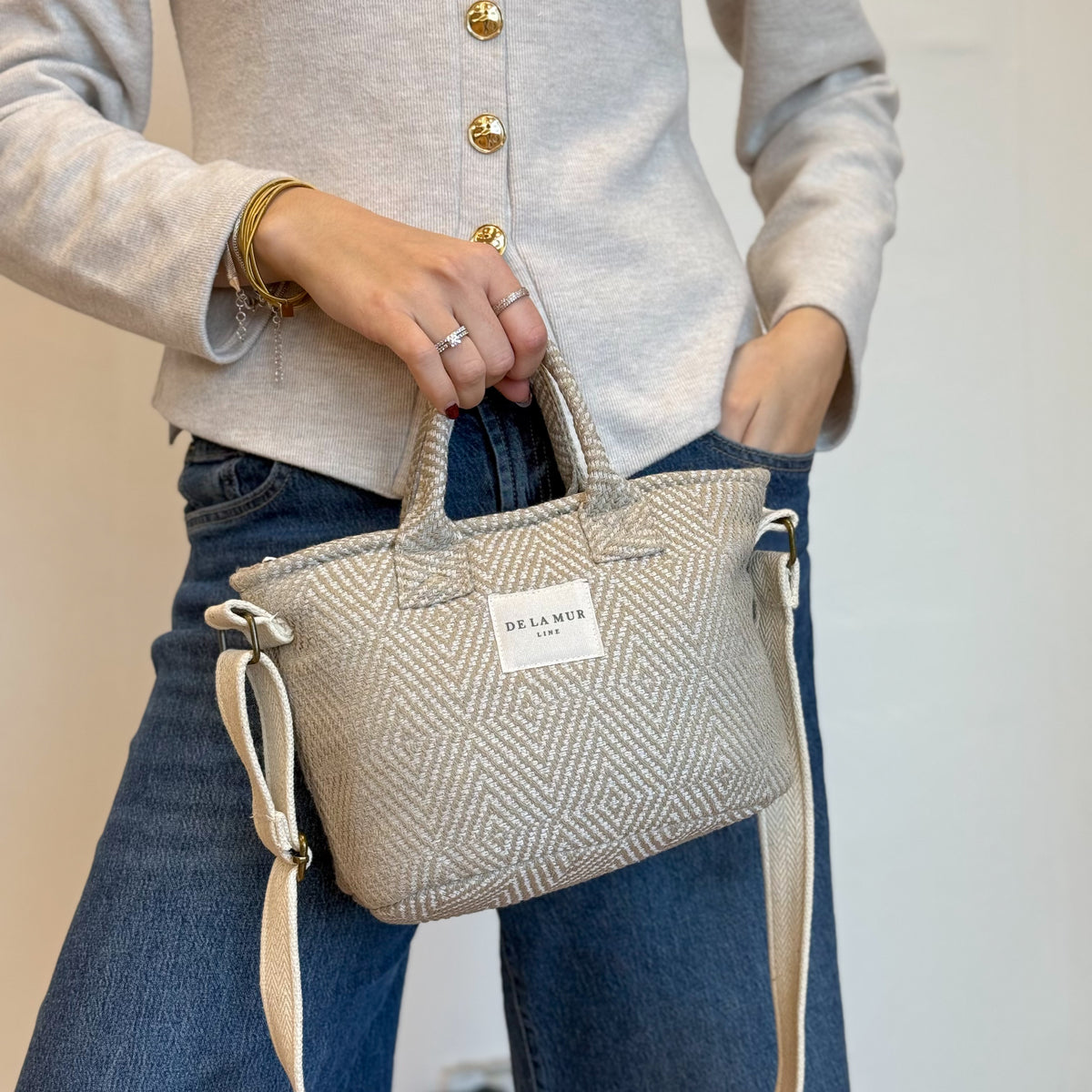 Model holding the DE LA MUR Arena geometric jacquard basket handbag, three-quarter view