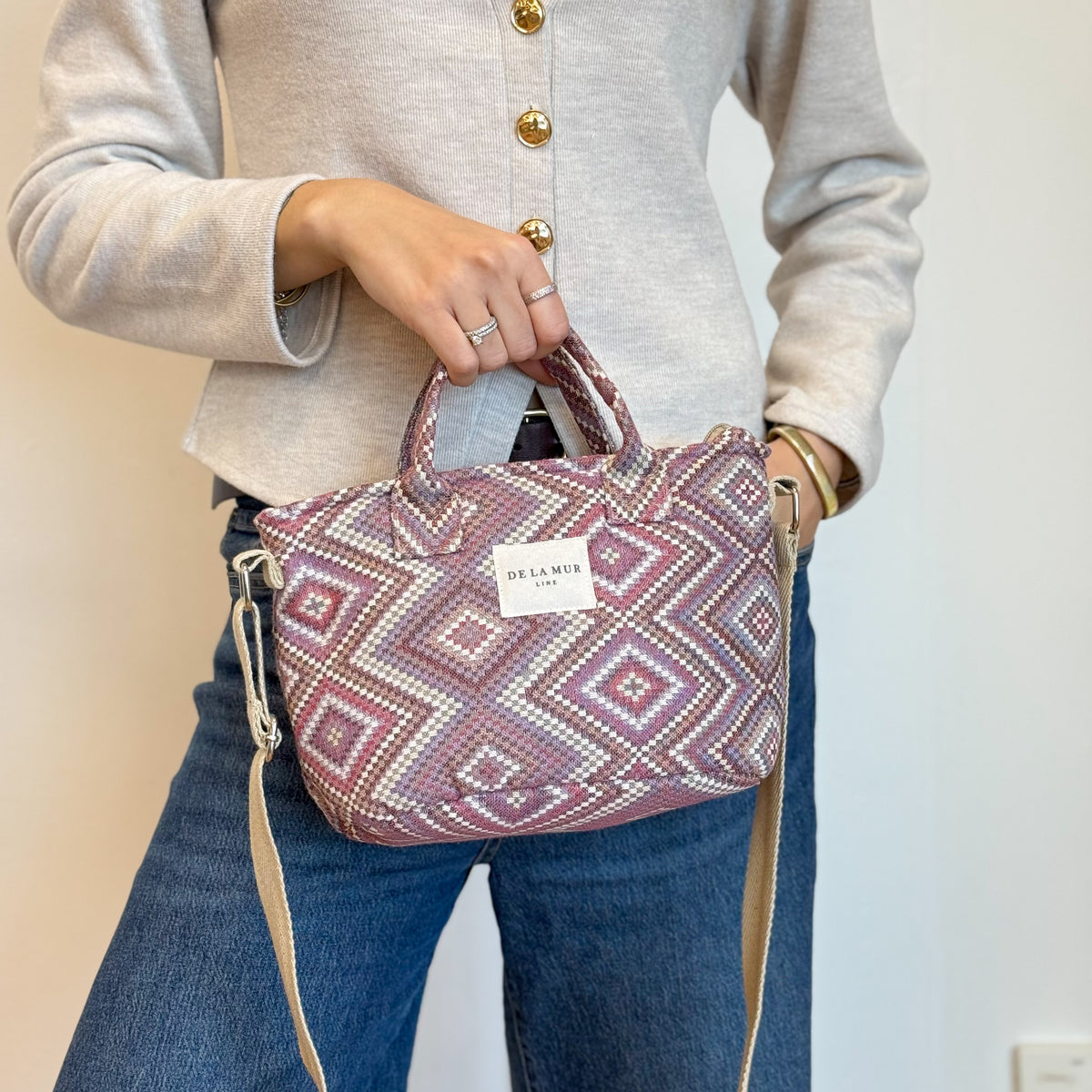 Model holding the DE LA MUR Nana beige and lilac jacquard basket handbag, three-quarter view