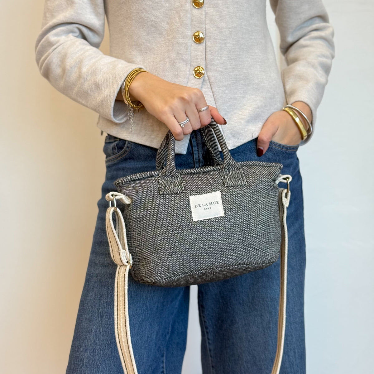 Model holding the DE LA MUR Sinay dark gray herringbone basket handbag, three-quarter view