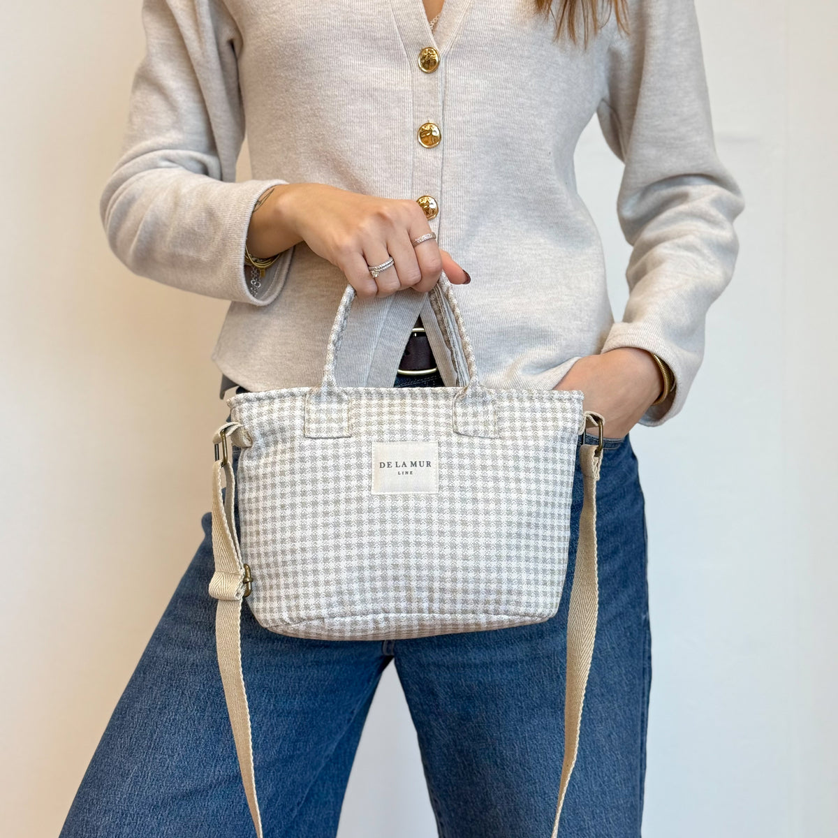 Model holding the DE LA MUR Vison beige gingham basket handbag, three-quarter view