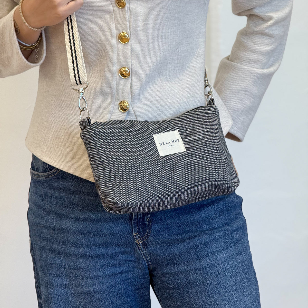 Model wearing the DE LA MUR Sinay striped jacquard clutch handbag, three-quarter view