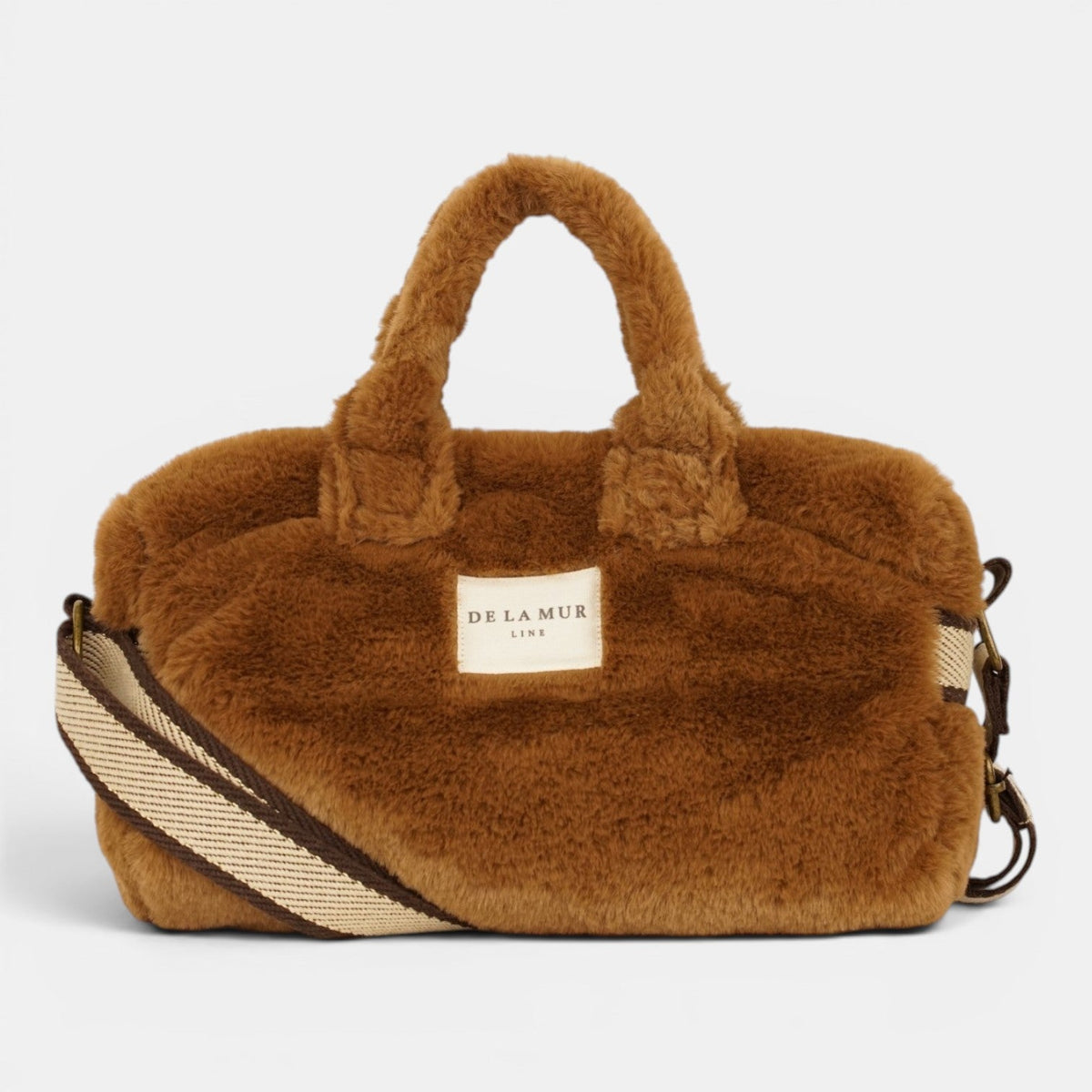 DE LA MUR camel brown faux fur small handbag, front view with striped crossbody strap and logo