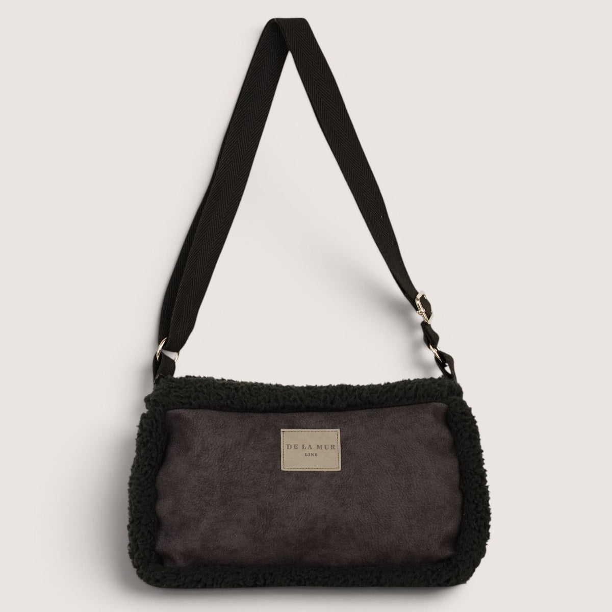 DE LA MUR Cene faux suede small shoulder bag in black, front view with adjustable strap