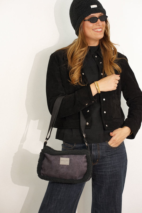 Model wearing the black DE LA MUR Cene faux suede small shoulder bag crossbody