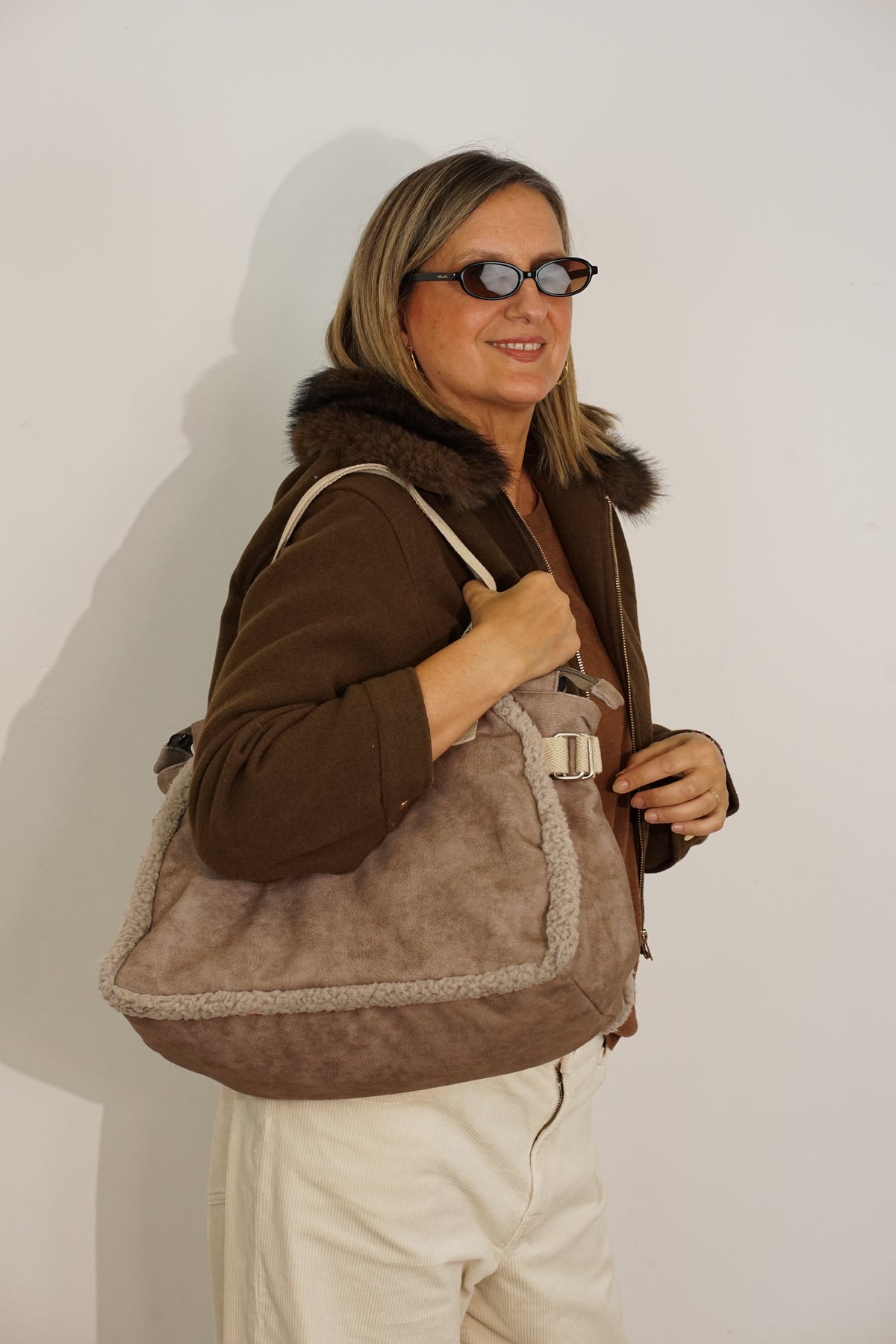 Woman wearing the taupe DE LA MUR Noce large shoulder bag over the shoulder, side angle