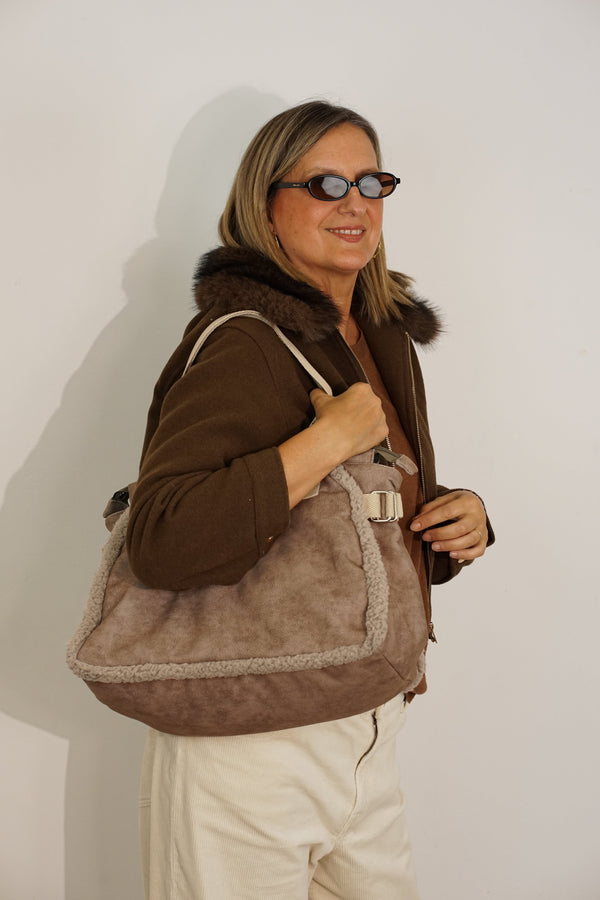 Woman wearing the taupe DE LA MUR Noce large shoulder bag over the shoulder, side angle