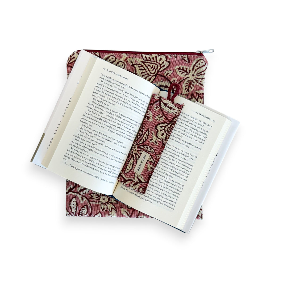 Open book with the DE LA MUR Came floral bookmark resting on the pink book cover