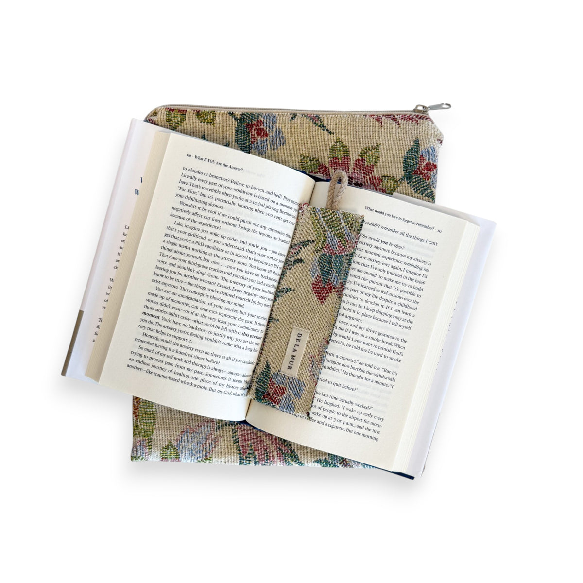 Open book with DE LA MUR Color floral bookmark resting on the multicolor book cover