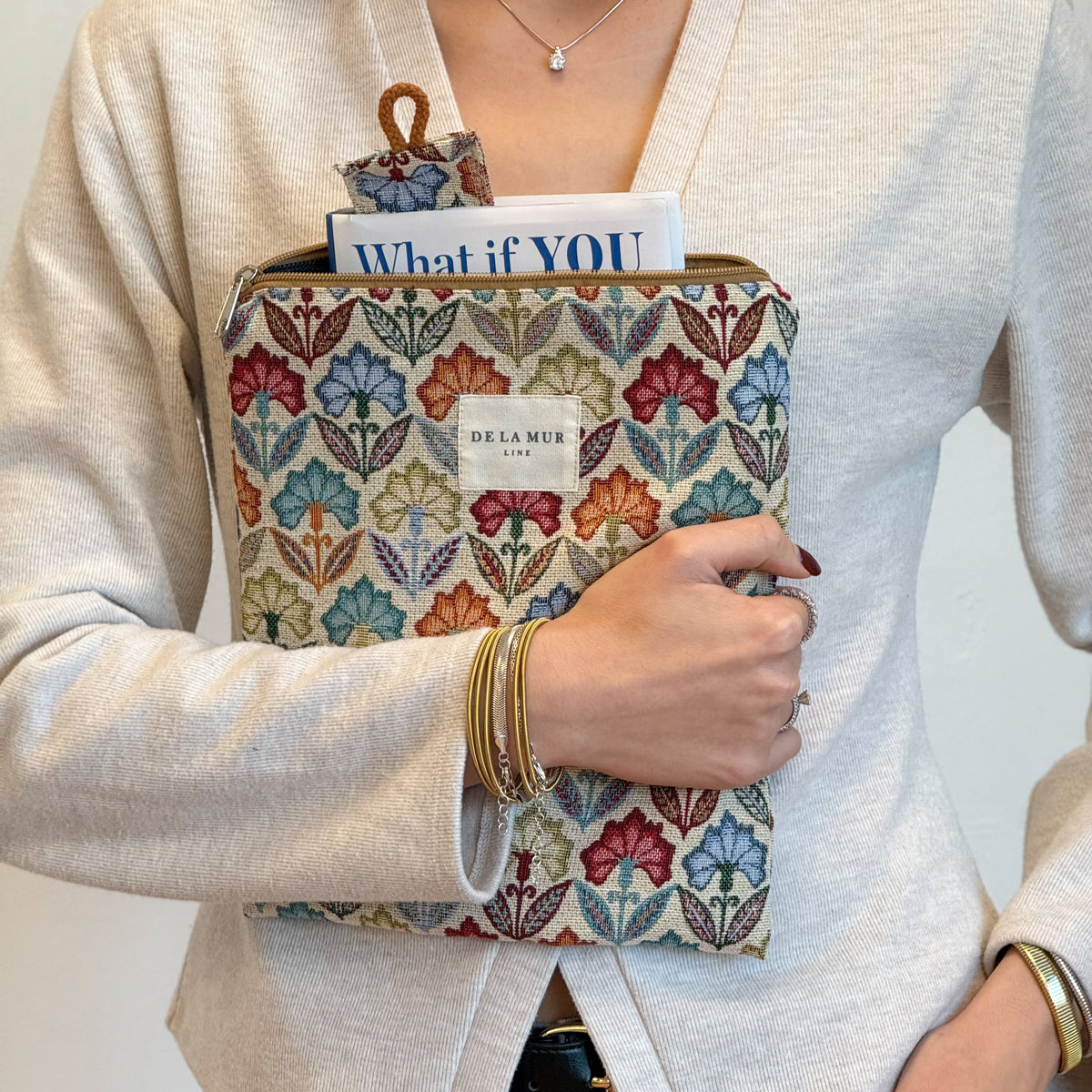 Model holding the DE LA MUR Flora floral jacquard book cover with book and bookmark