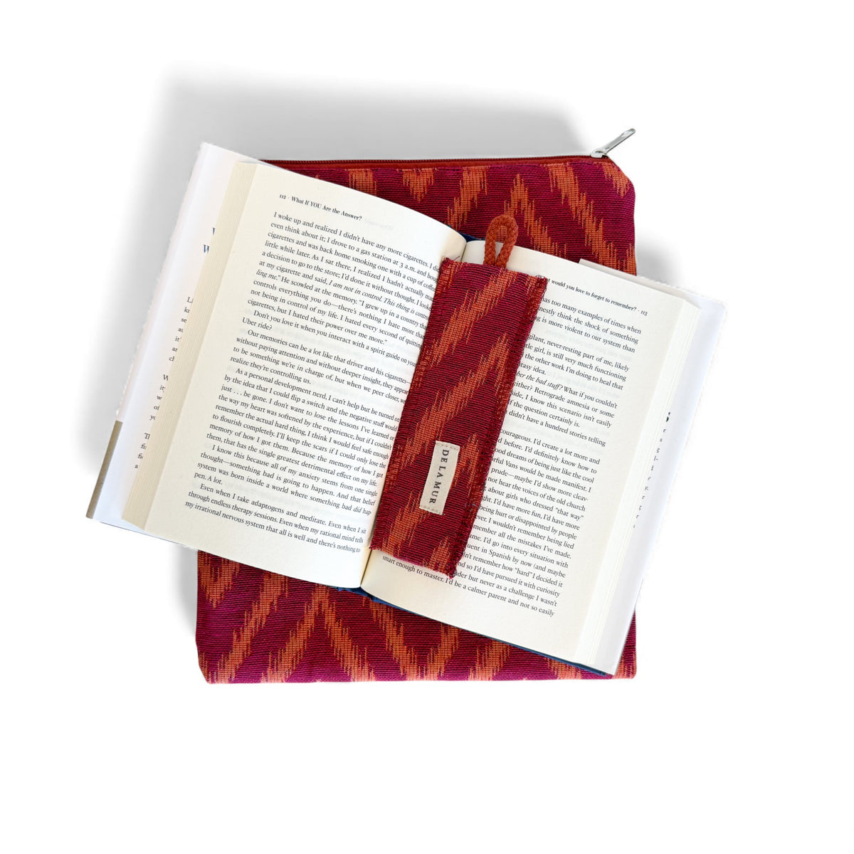 Open book resting on the DE LA MUR Fuego cover with the matching bookmark in place