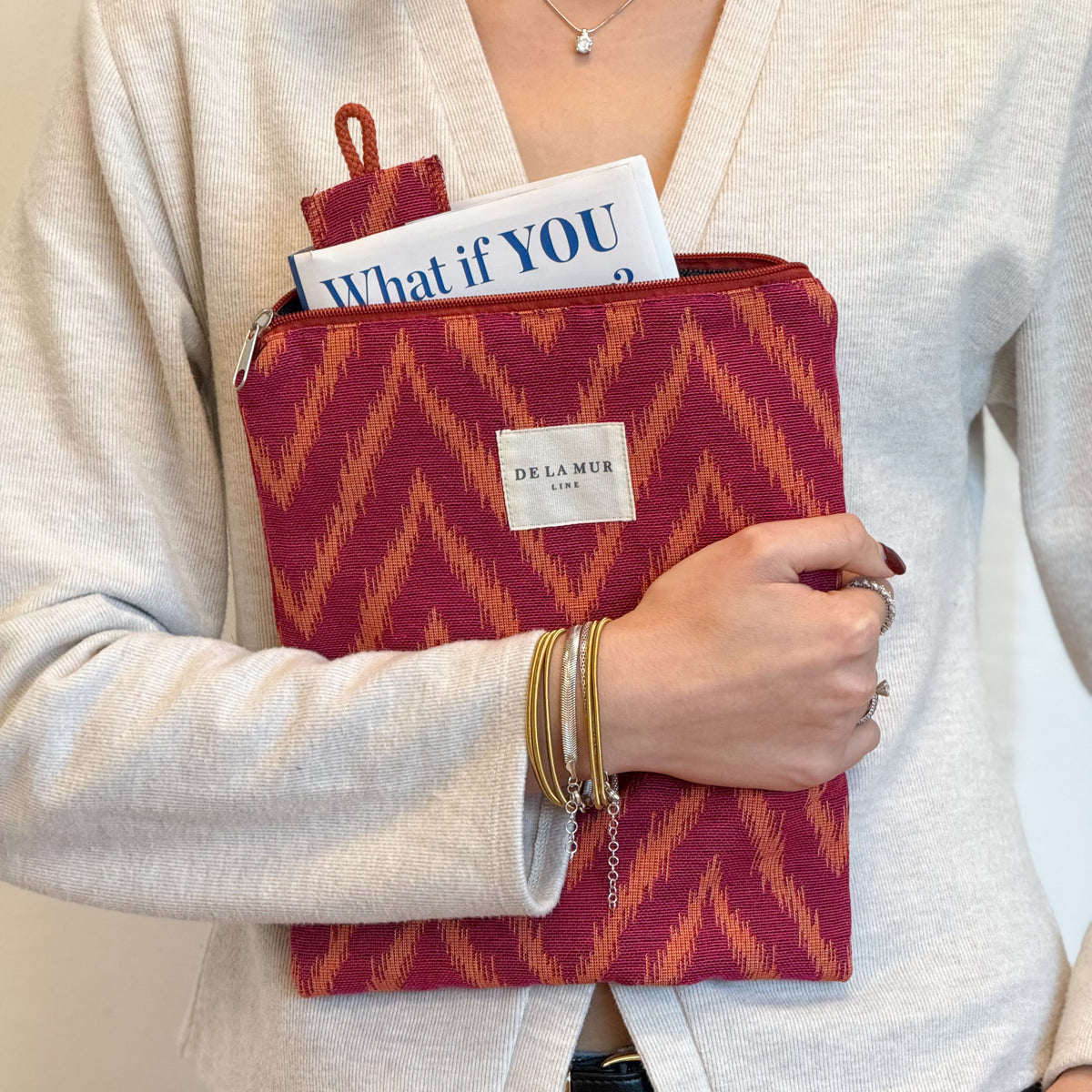 Model carrying the DE LA MUR Fuego book cover and matching bookmark close against her cardigan