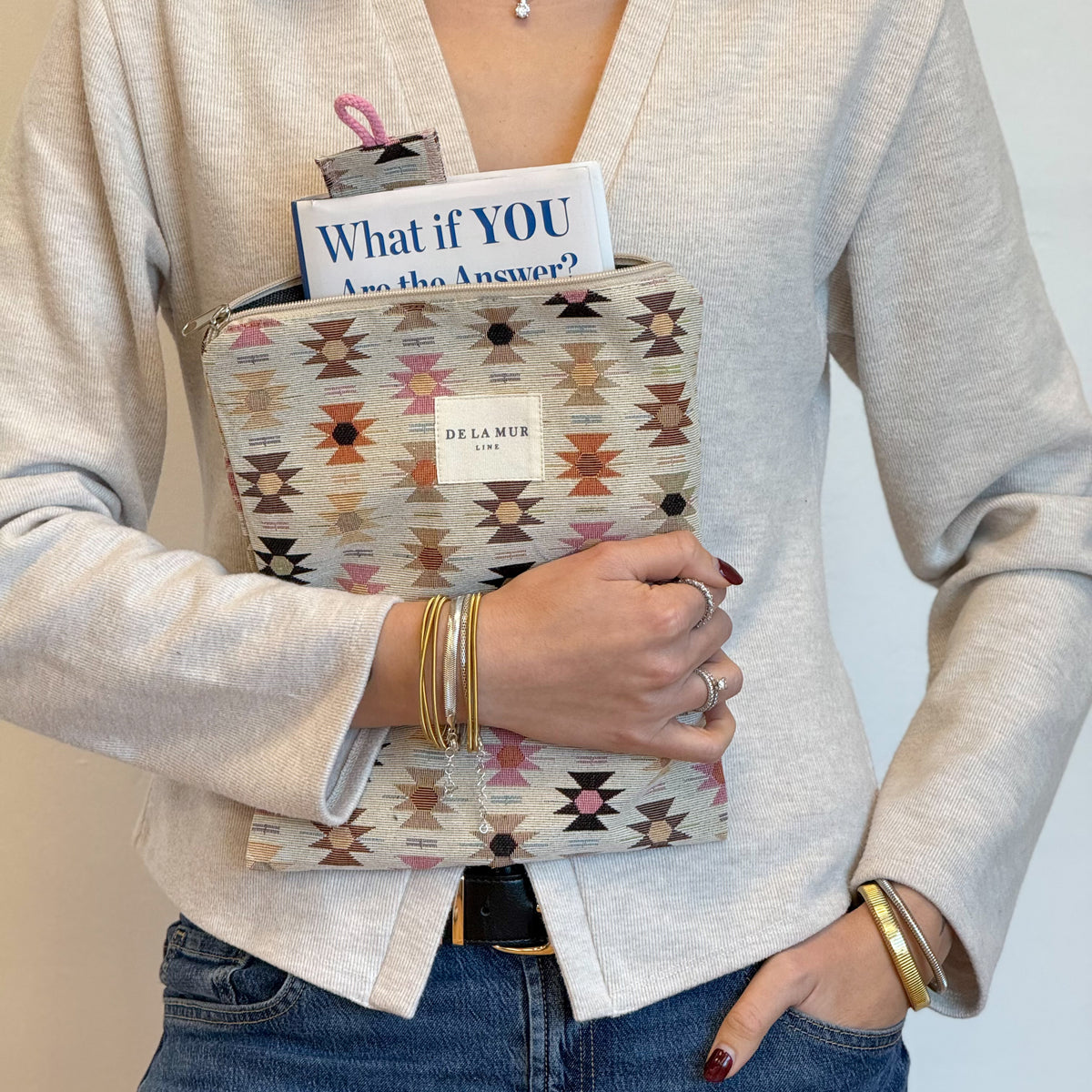 Model carrying the DE LA MUR Royal geometric book cover and bookmark against her cardigan