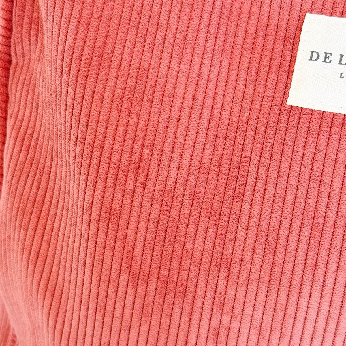 Close-up of the coral corduroy fabric and DE LA MUR Line label