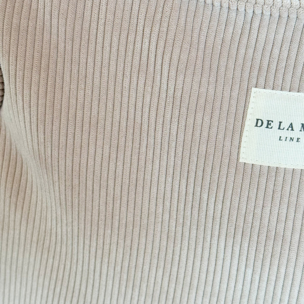 Close-up of the beige corduroy fabric and DE LA MUR Line label