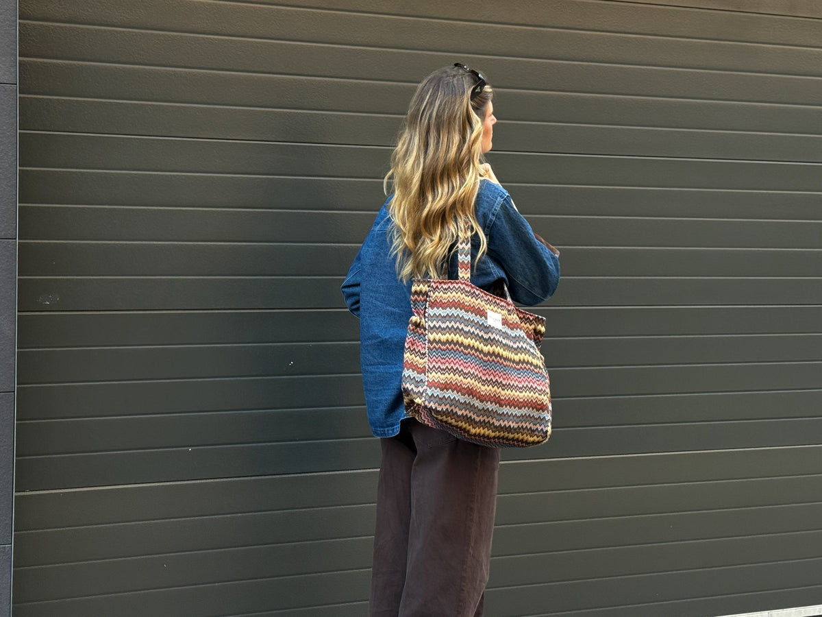 Model carrying the DE LA MUR Monte zigzag jacquard tote bag over the shoulder