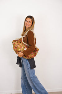Model carrying the DE LA MUR mustard and red floral jacquard tote on the shoulder
