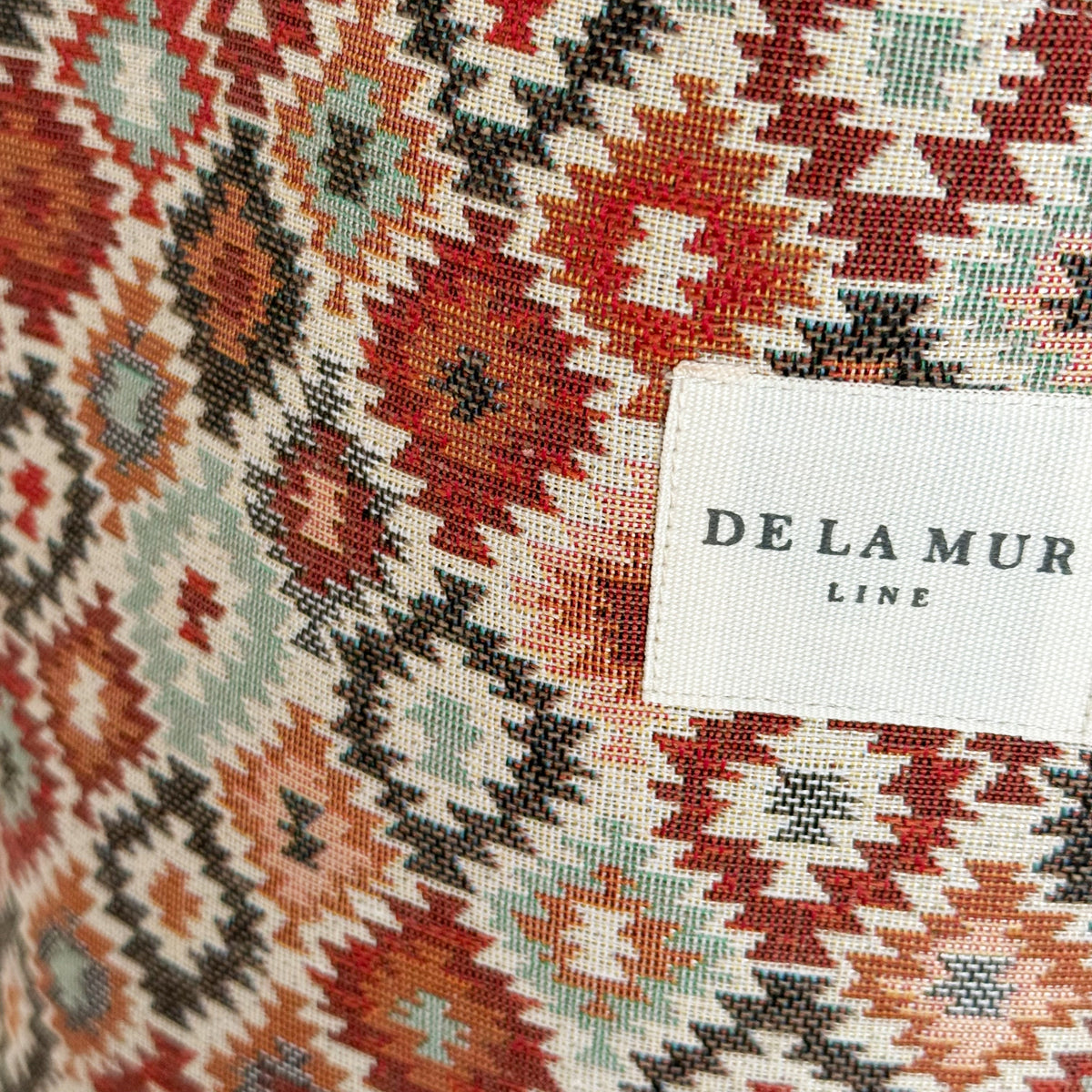 Close-up of the geometric diamond jacquard weave and DE LA MUR Line label