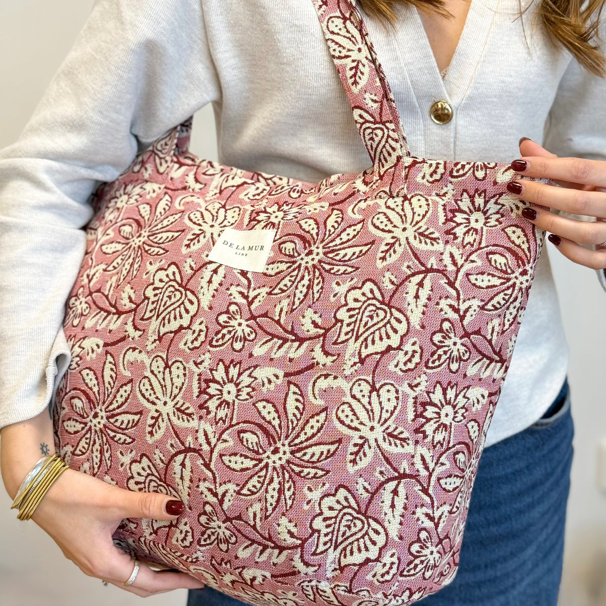 Model holding the rose floral DE LA MUR Came tote, three-quarter view