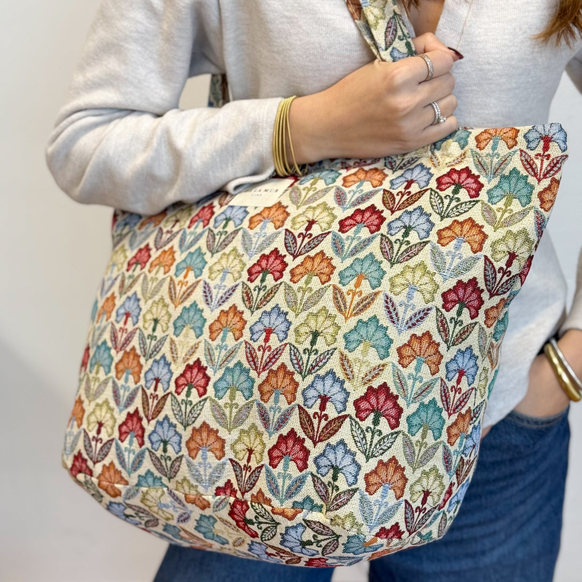Model holding the multicolor DE LA MUR Flora tote, three-quarter view