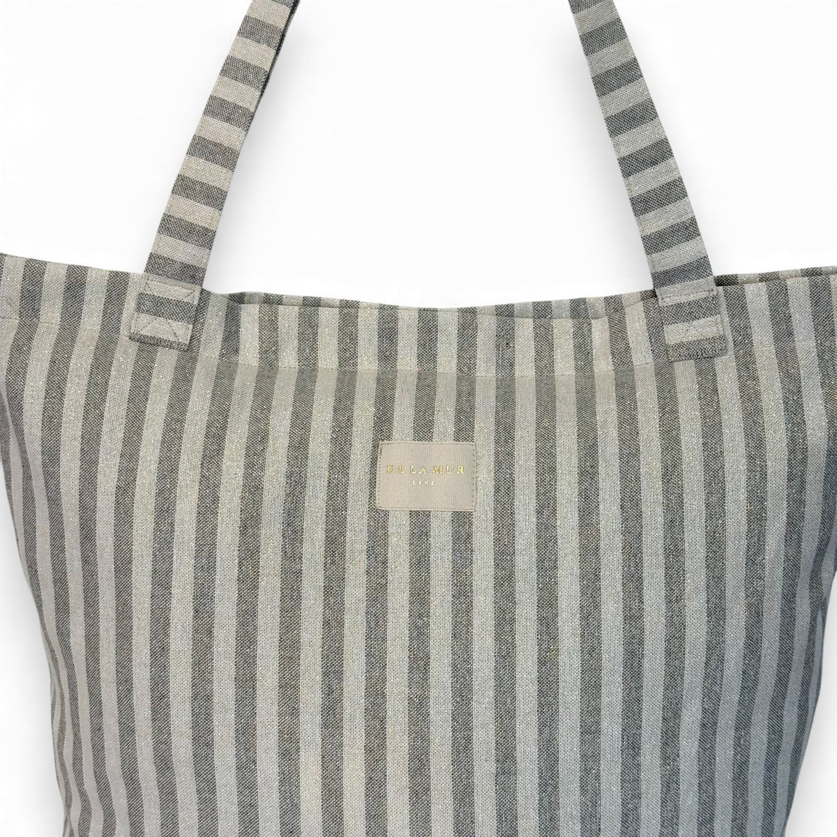 Close-up of the DE LA MUR Line label and gray striped fabric on the tote