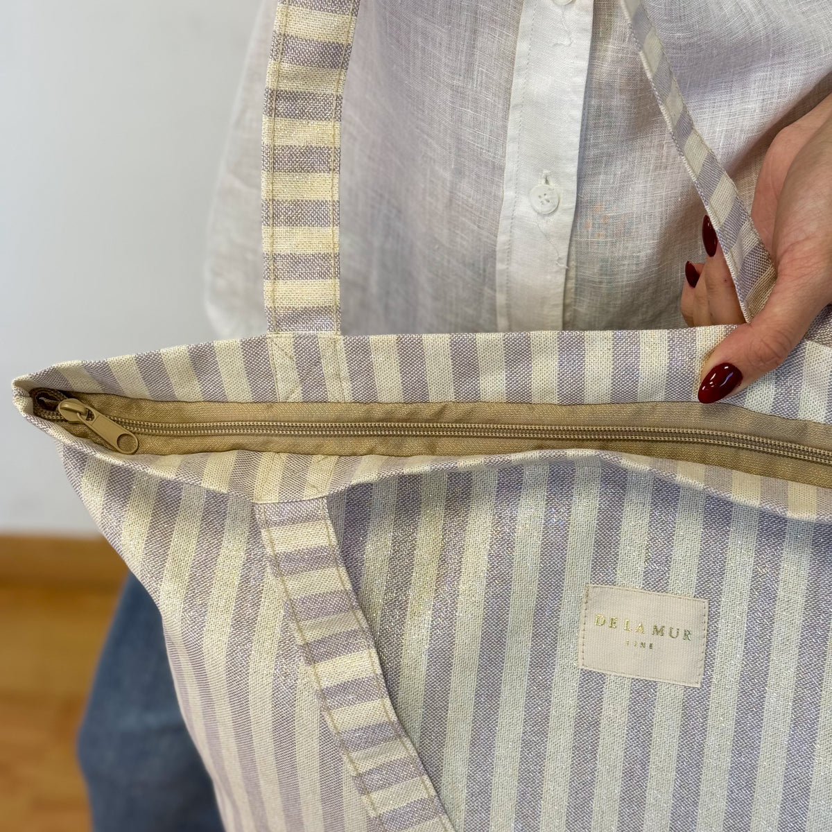 Close-up of the DE LA MUR lilac striped tote zip and DE LA MUR Line label