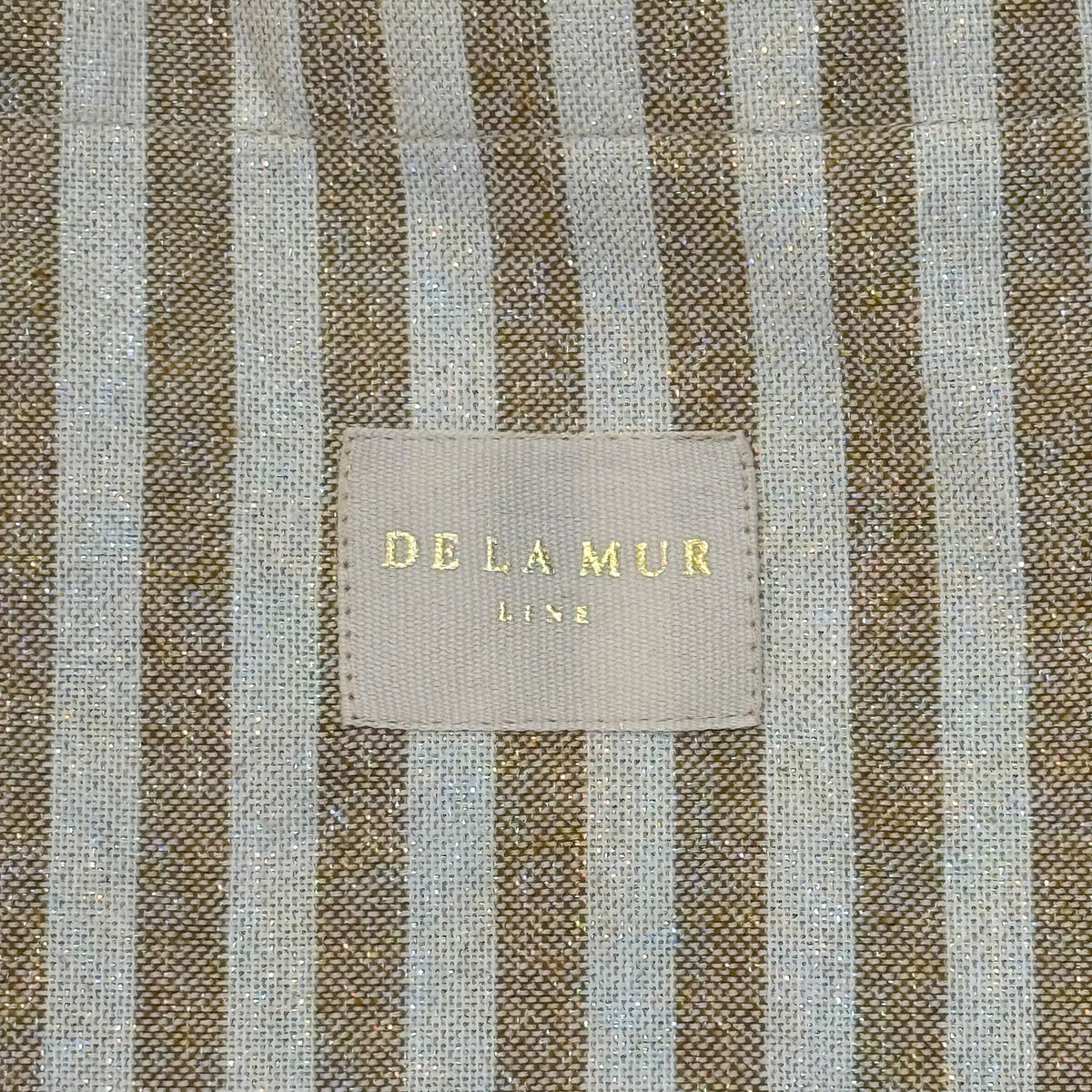 Close-up of the gold-flecked mustard striped fabric and DE LA MUR Line label