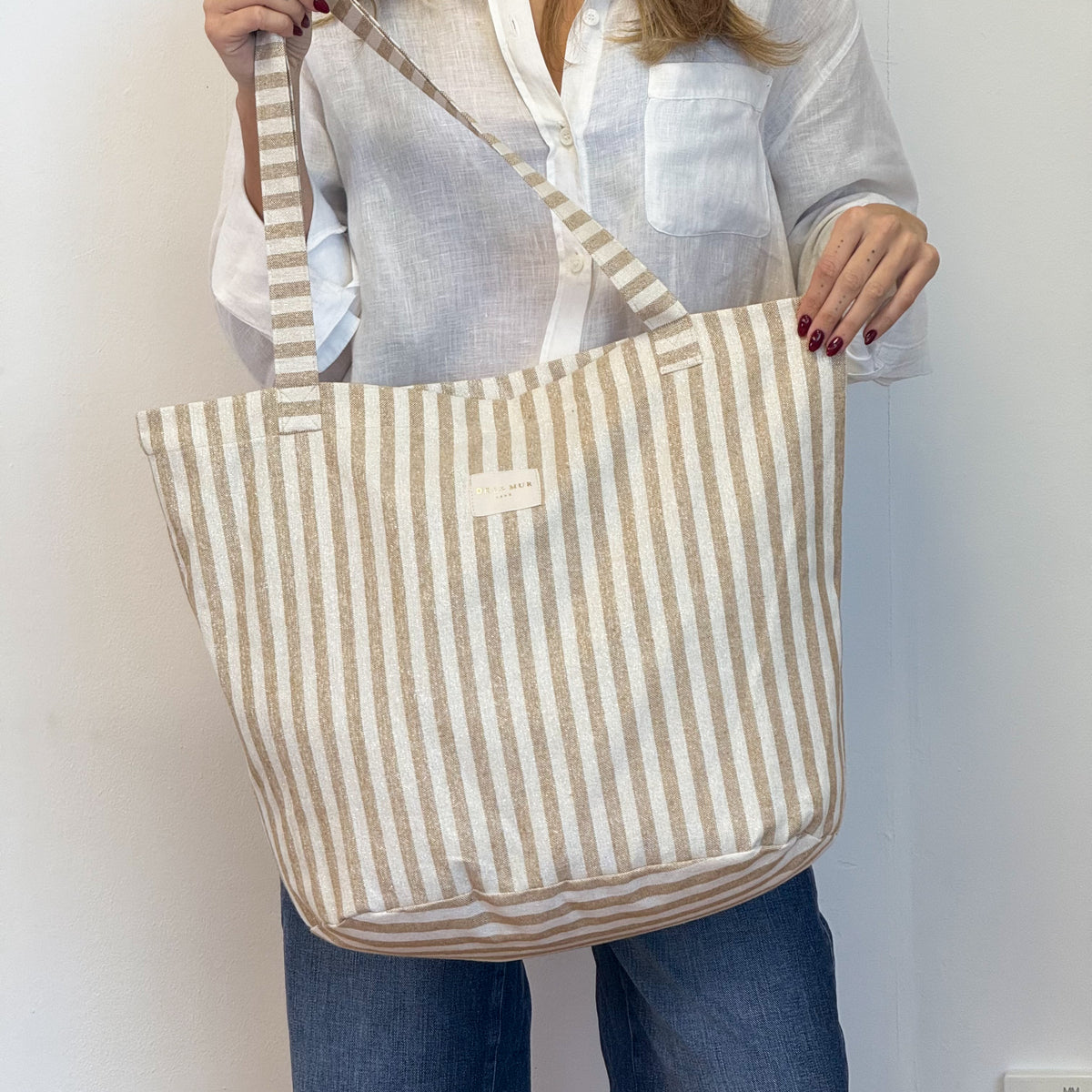 Model wearing the DE LA MUR mustard striped tote bag over the shoulder