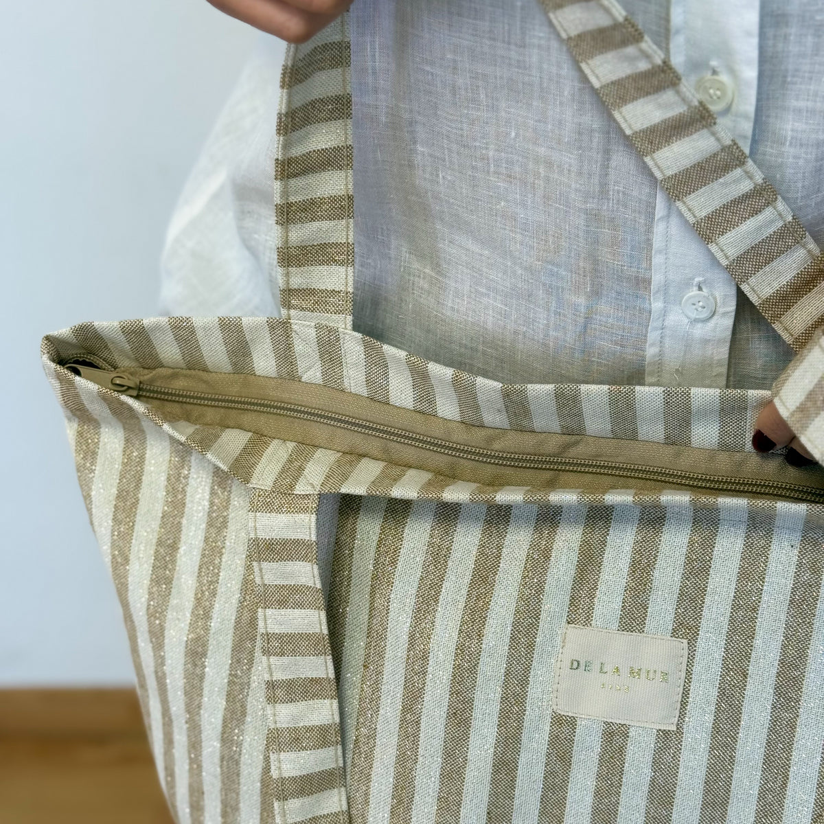 Close-up of the DE LA MUR mustard striped tote zip and lined interior