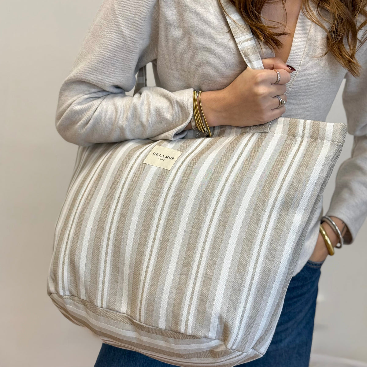 Model wearing the DE LA MUR beige striped jacquard tote over the shoulder