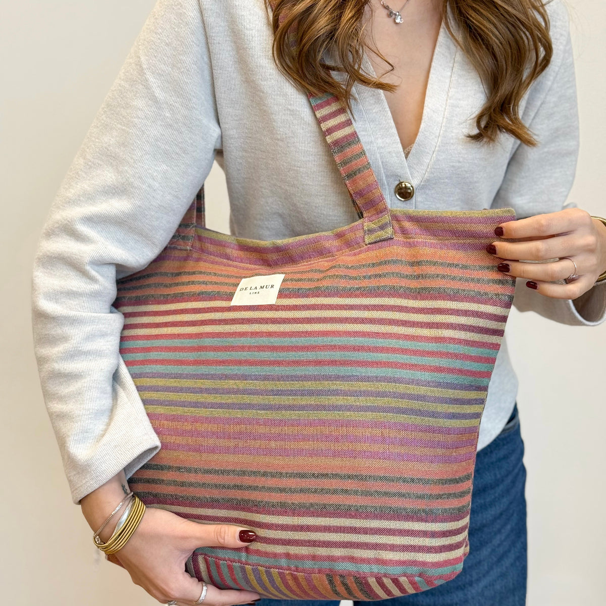 Model wearing the DE LA MUR multicolor striped jacquard tote on the shoulder
