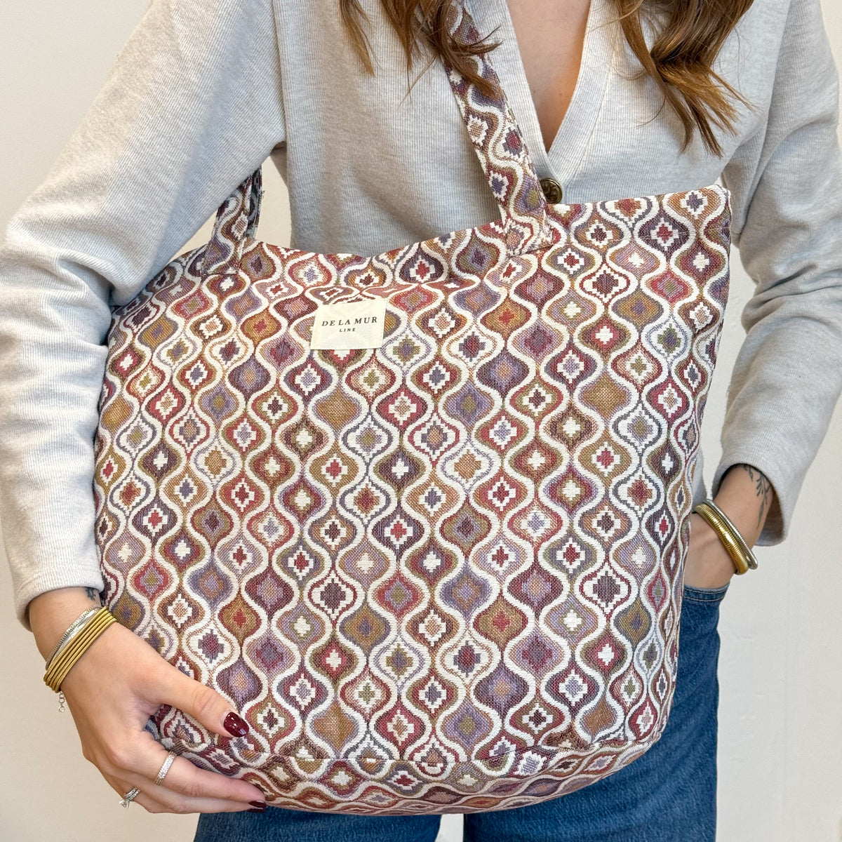 Model carrying the DE LA MUR Onda geometric jacquard tote on the shoulder