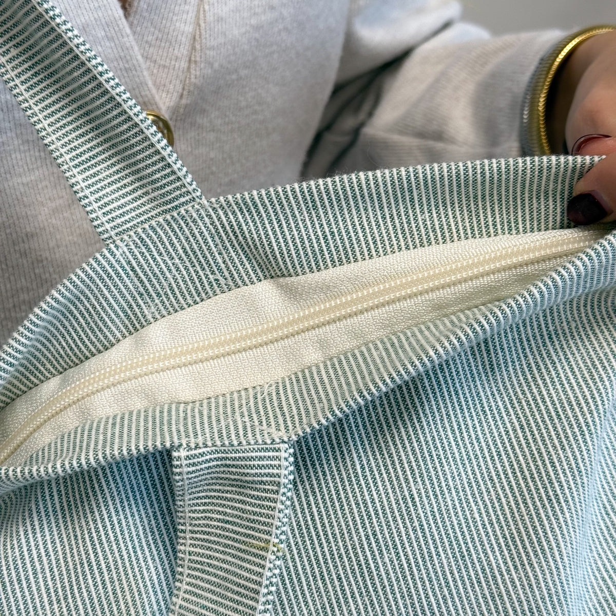 Detail of the open ivory zip closure on the DE LA MUR Teo striped tote bag