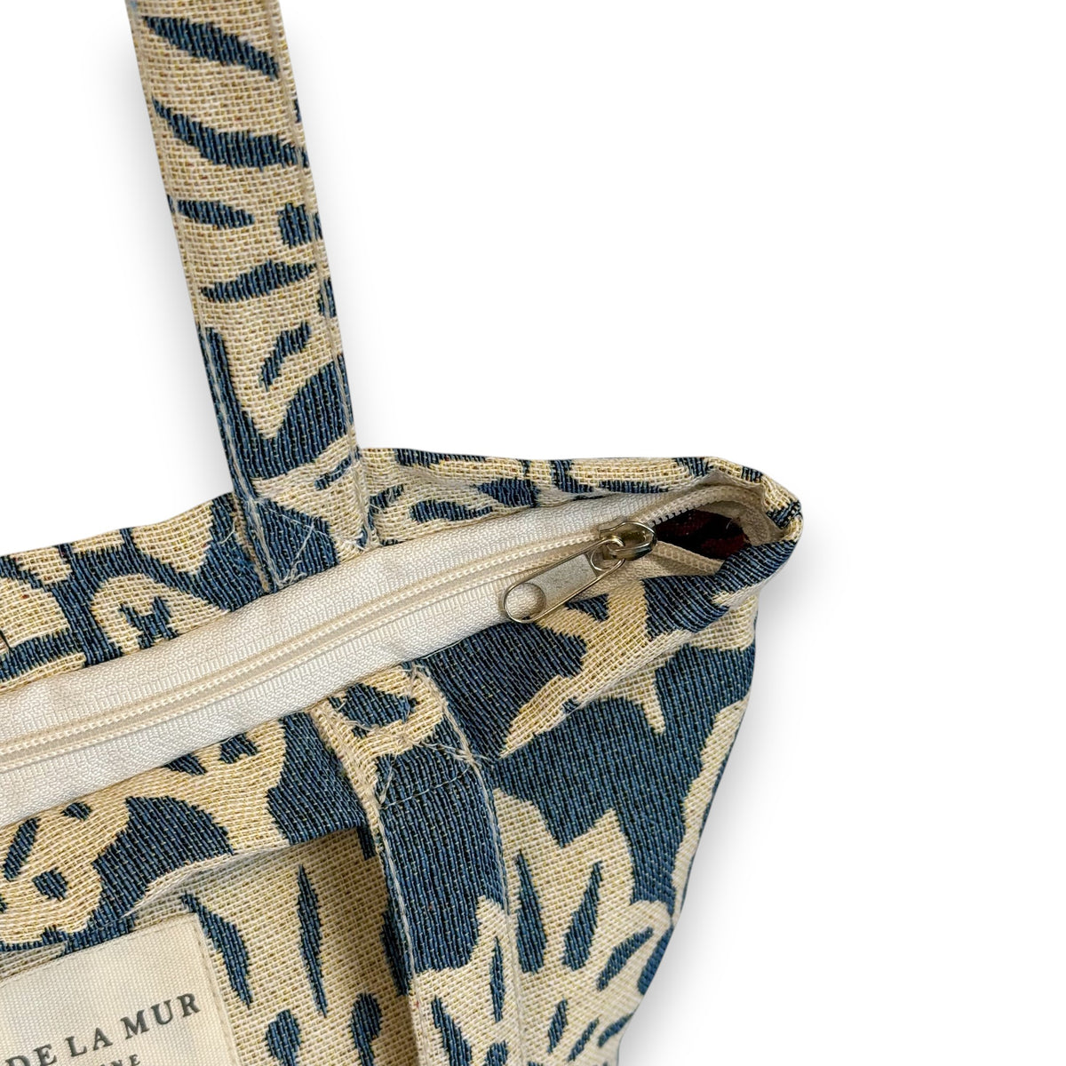 Close-up of the top zip and DE LA MUR Line label on the Akay floral jacquard bag