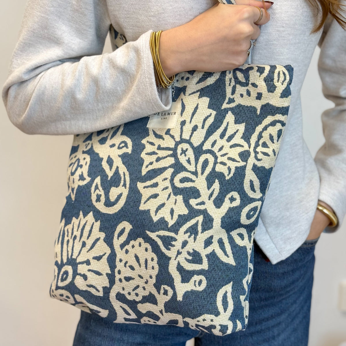 Model carrying the DE LA MUR Akay blue floral jacquard bag on the shoulder
