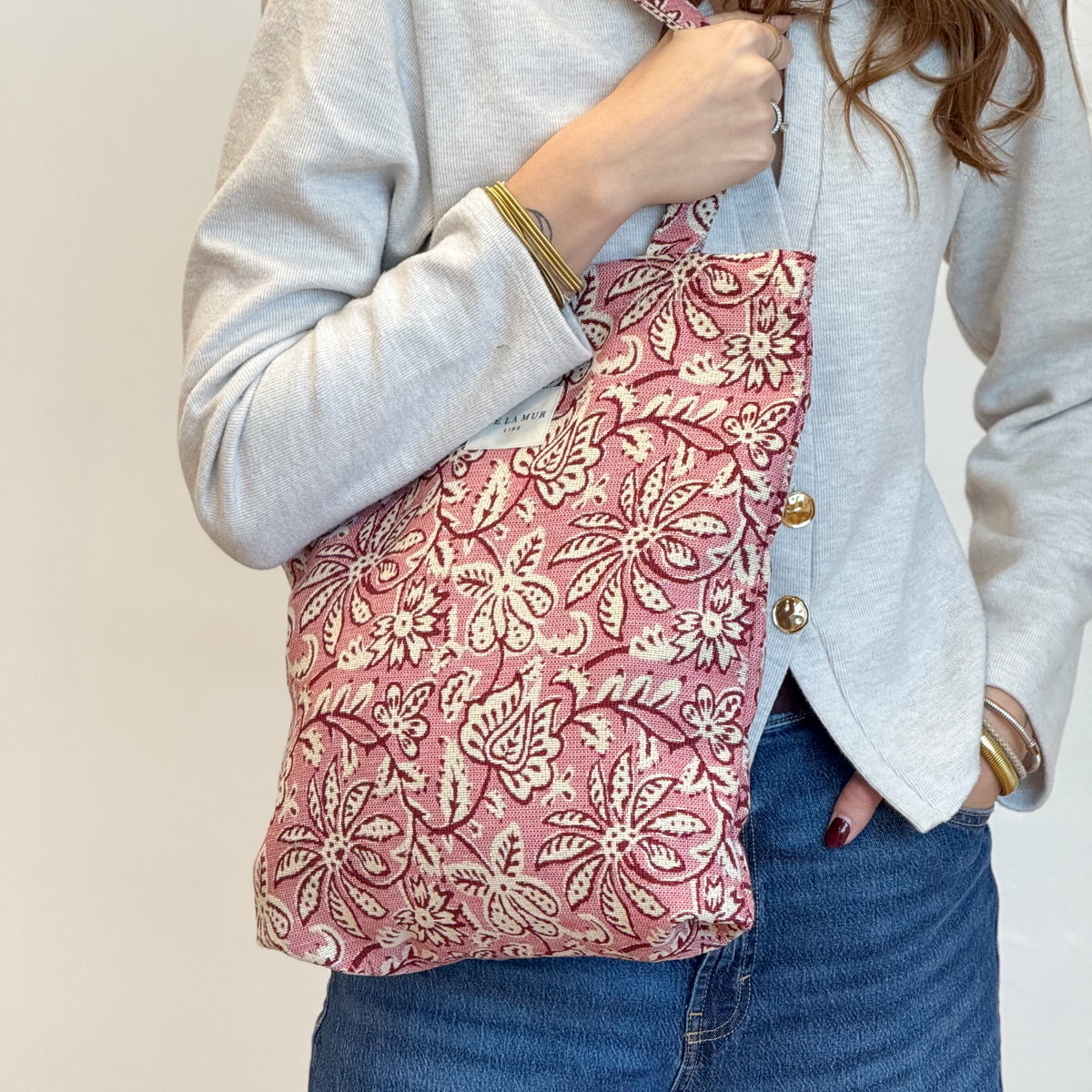 Model holding the DE LA MUR pink floral jacquard zippered bag